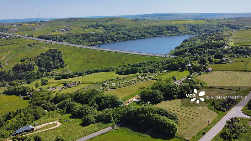 高角度俯瞰生机勃勃的绿色农田，湖泊和公路在晴朗的天空下图片素材
