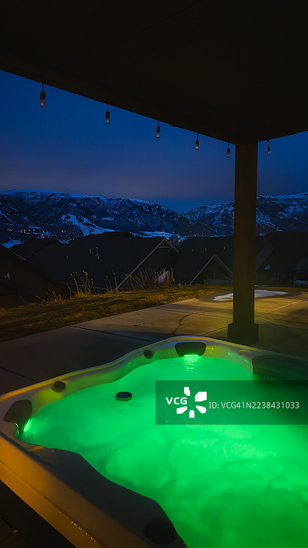 黄昏时分，温泉沐浴区沐浴着鲜亮的绿光，俯瞰着白雪皑皑的山景，地点：美国图片素材