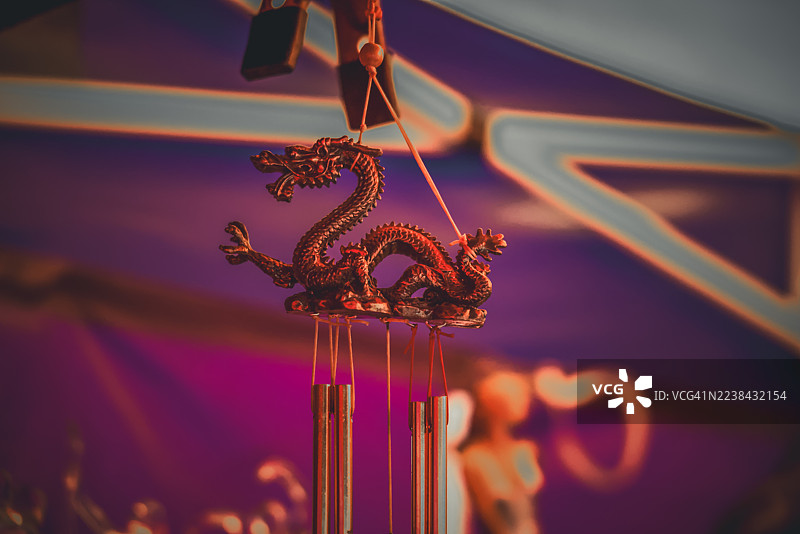天花板上悬挂着龙形风铃的特写，背景是鲜艳的紫色和蓝色。图片素材