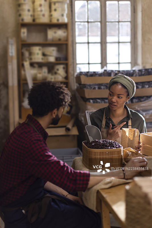两名顾客在一家乡村市场商店讨论食品杂货，店内有咖啡豆和木桶。图片素材