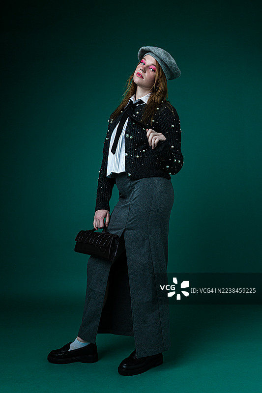 身穿画家帽和珍珠毛衣的时尚女子，手拿手袋图片素材