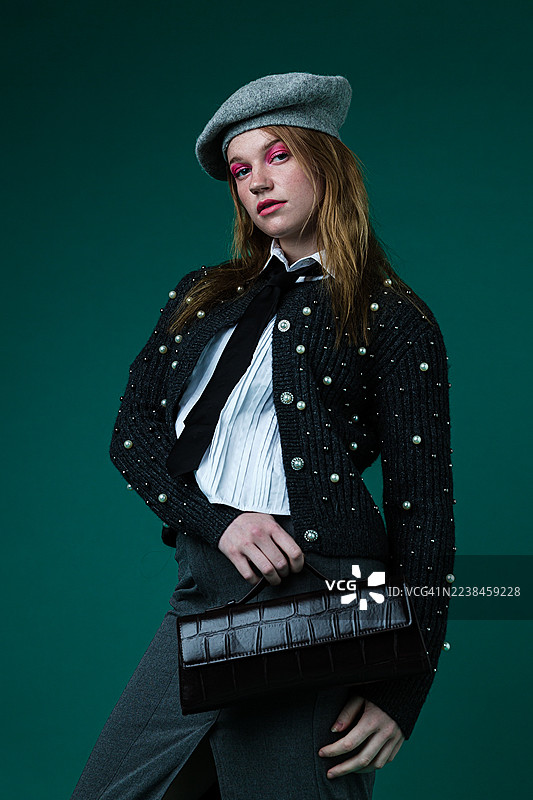 身着画家帽和珍珠毛衣、手拿手袋的时尚女士图片素材