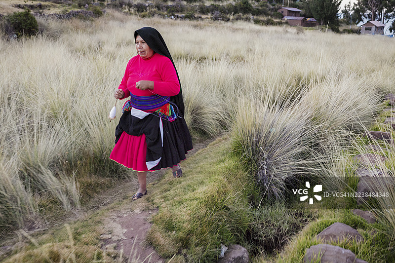 秘鲁的的喀喀湖塔基尔岛上一位妇女正在手工纺羊毛图片素材