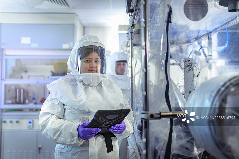 实验水晶实验室里的科学家，配有数码平板和隔离手套箱图片素材