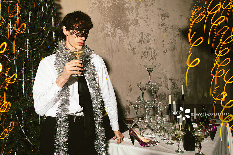 佩戴假面舞会面具的男士在节日派对上饮用香槟图片素材