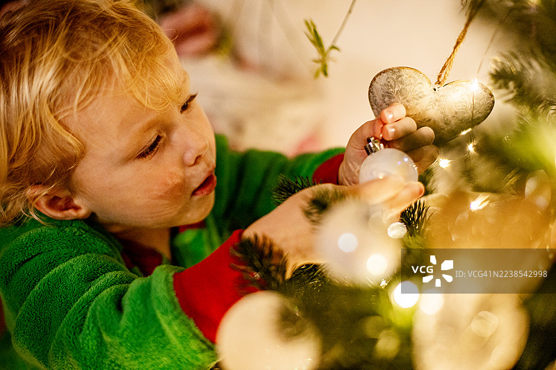 小男孩伸手去拿圣诞树上的装饰品图片素材