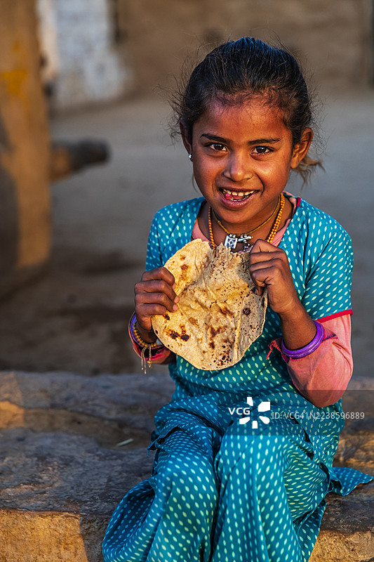 印度小女孩在沙漠村庄吃印度薄饼（一种扁平面包）图片素材