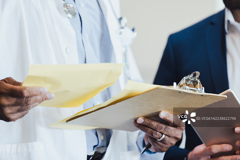 医生和商人正在审阅医疗文件和药片，并讨论病人护理图片素材