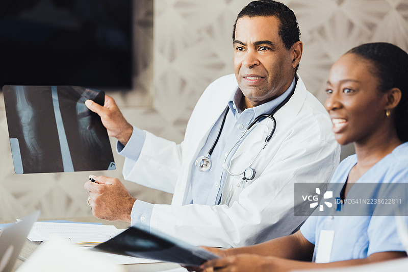 医疗专业人士在会议上讨论患者的X光片，展示了团队合作和医疗专业知识。图片素材