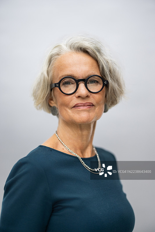 戴眼镜、留着一头干练灰发的时尚成熟的女模特图片素材