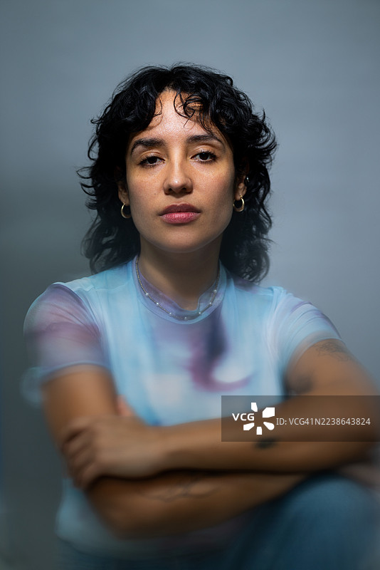 年轻的拉丁裔女性模特，身着时尚服装，背景为灰色。图片素材