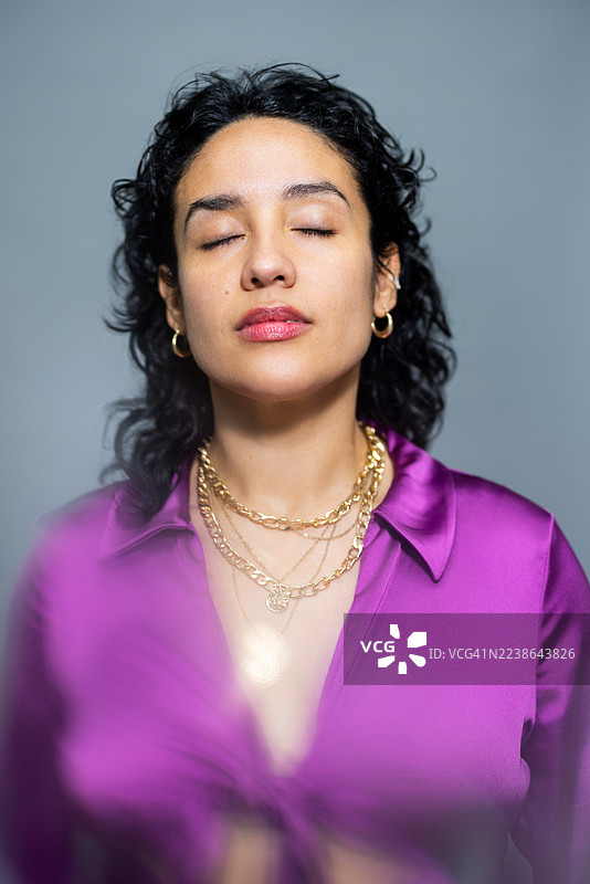身穿紫色衬衫、闭着眼睛的西班牙裔美女模特，背景为灰色图片素材