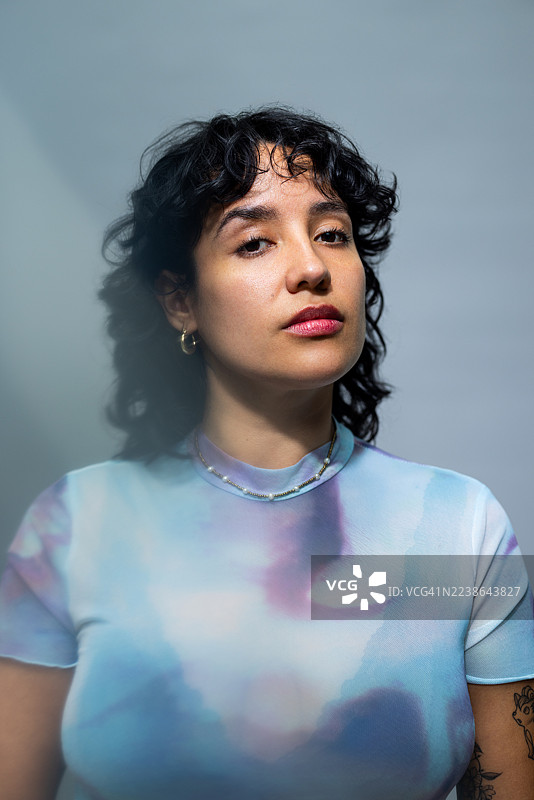 时髦的西班牙裔女性模特身着时尚服装，若有所思地摆姿势。图片素材