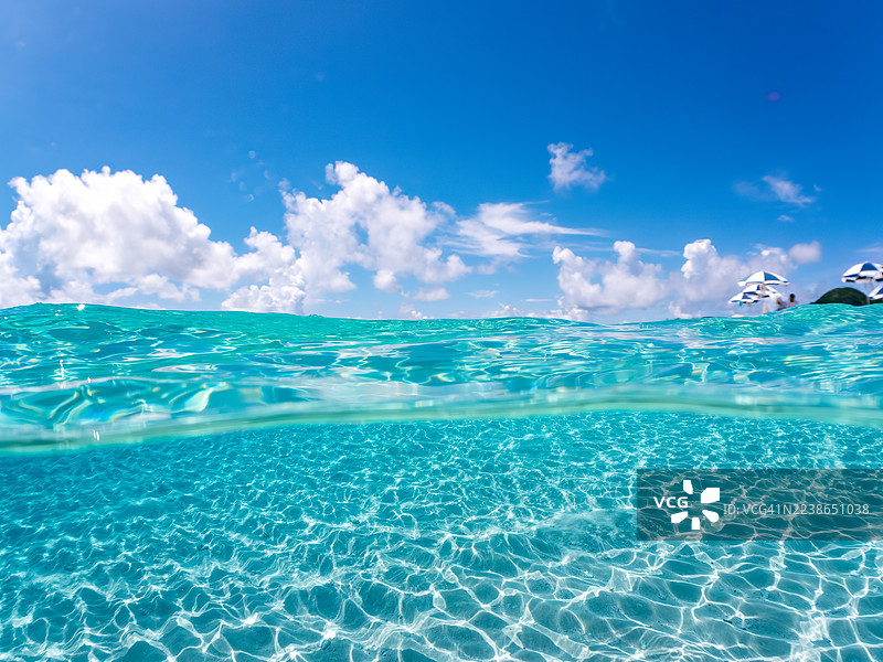 航拍美丽白沙滩的一半。可以看到遮阳伞、船只,甚至还有冲绳特有的双体船 Sabani。一群热带鱼。美丽的珊瑚礁和游泳的人们。位于冈比亚岛、座间味岛、庆良间群岛。图片素材