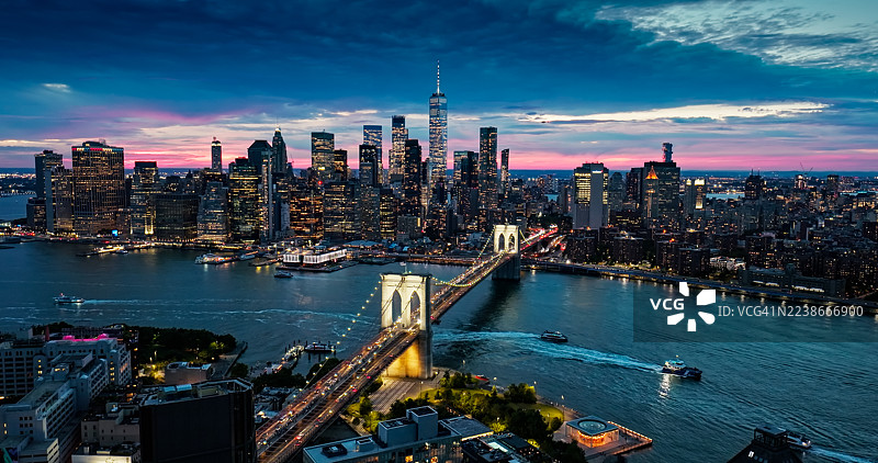 无人机视角拍摄的纽约市布鲁克林大桥和曼哈顿下城在黄昏时的景象图片素材