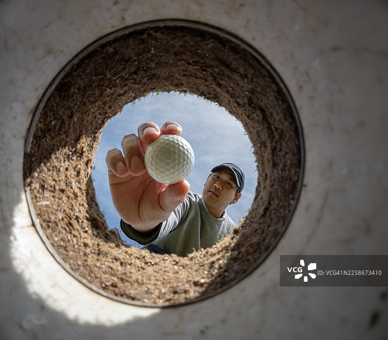 男人从洞里取出高尔夫球的第一视角图片素材