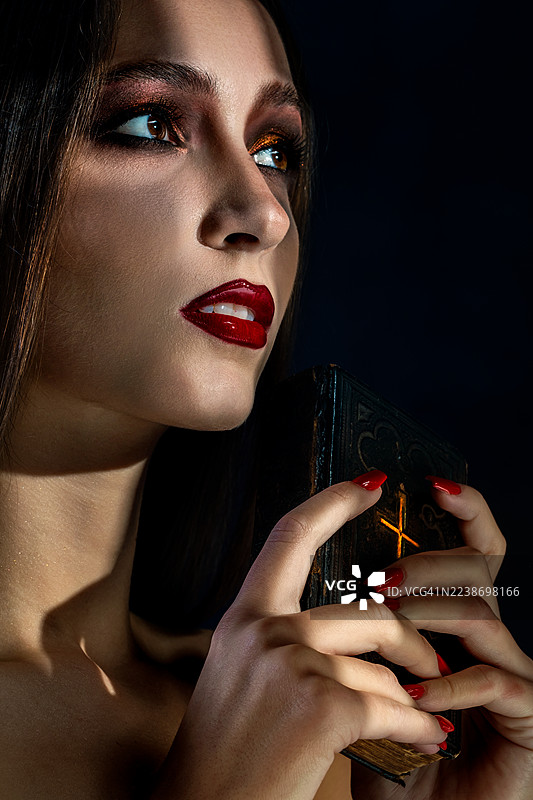 一位化着浓妆的女子手持一本圣书图片素材