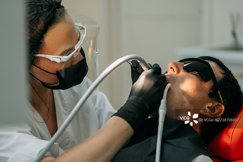 牙医在牙科诊所为患者治疗牙齿图片素材