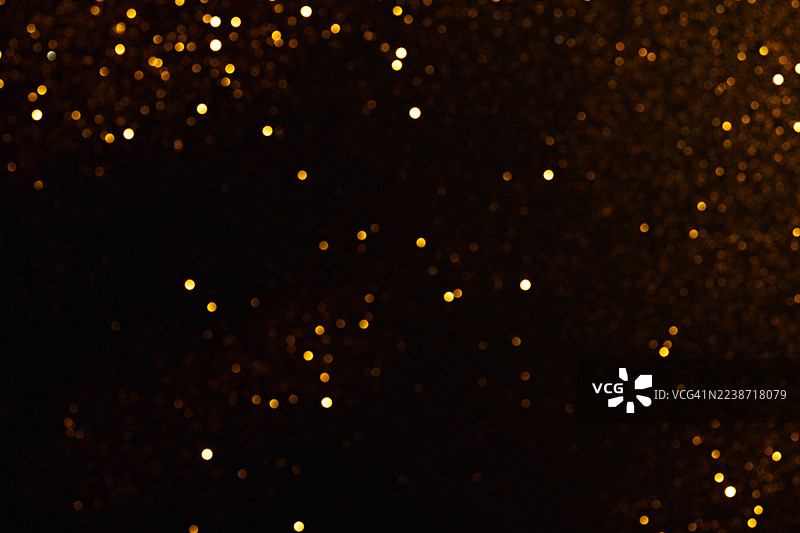 深色背景上丰富的金色散景纹理。图片素材
