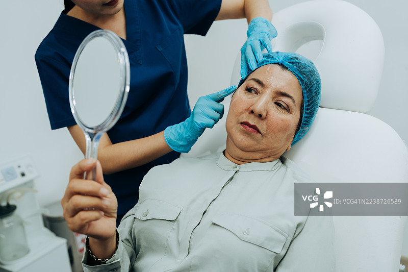 经验丰富的女性在接受整形外科医生咨询时，手中拿着镜子图片素材