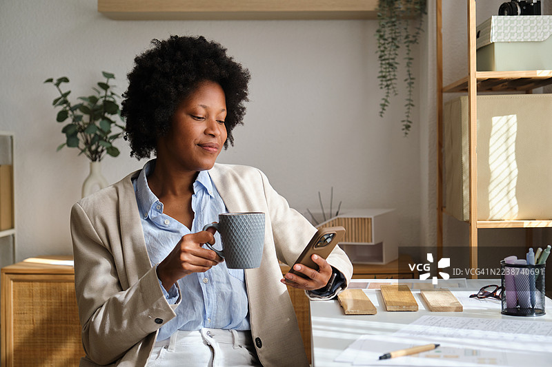 一位黑人女建筑师在办公室工作并使用智能手机。图片素材