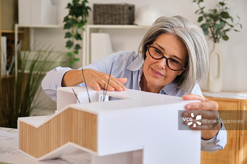 成熟的女建筑师在办公室里检查建筑模型图片素材