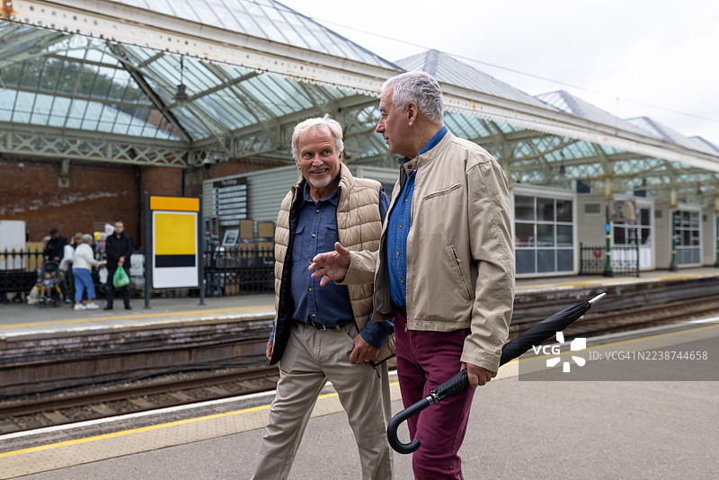 年长朋友们在火车站台上边走边聊天图片素材