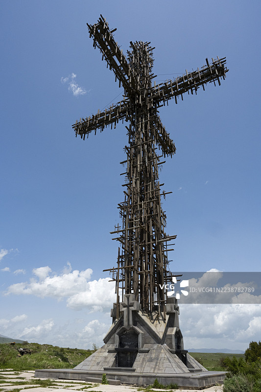蓝天白云下，一座结构复杂的金属十字架，由许多小型金属十字架组成，是亚美尼亚阿拉加措特恩省阿帕兰的圣十字纪念碑。图片素材