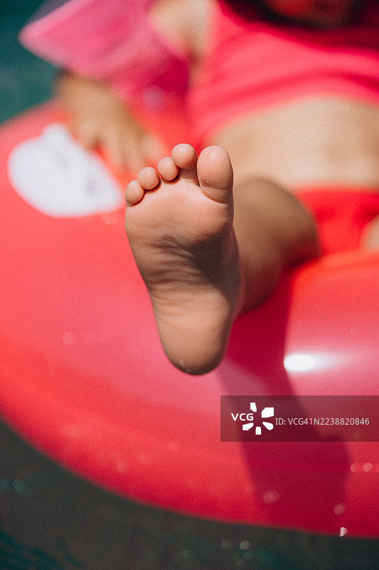 孩子光着的脚丫放松地放在泳池中的充气圈上图片素材