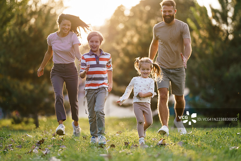 夕阳下，幸福的一家人在公园里奔跑图片素材