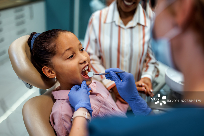 女牙医正在检查一个小女孩的牙齿图片素材