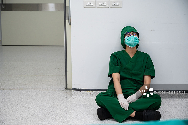 医疗工作者在医院因手术失败而感到压力和悲伤，坐在地板上。图片素材