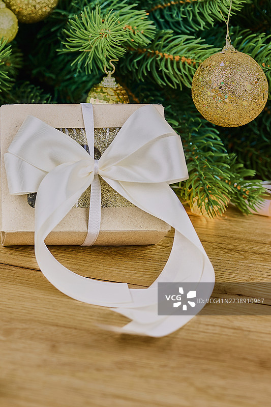 圣诞树下的白色丝带礼品盒，配有金色装饰品和松枝图片素材