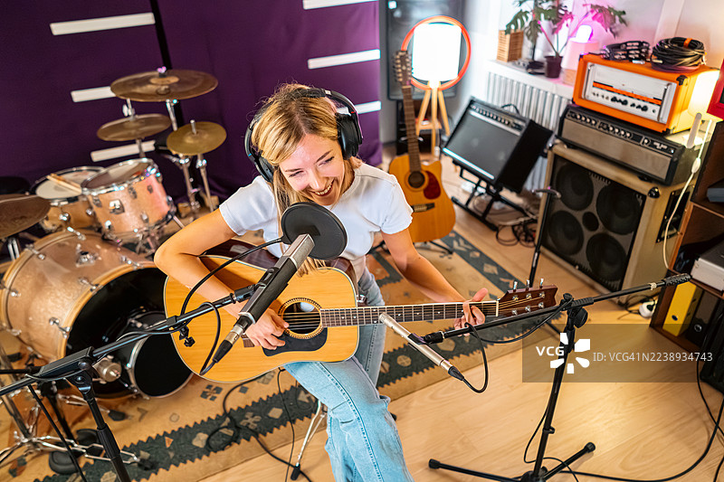 女音乐家在录音棚里进行声音检查时弹奏木吉他图片素材