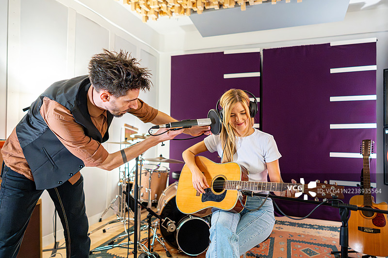 女音乐家在录音室进行声音检查时，现场弹奏原声吉他进行录制。图片素材