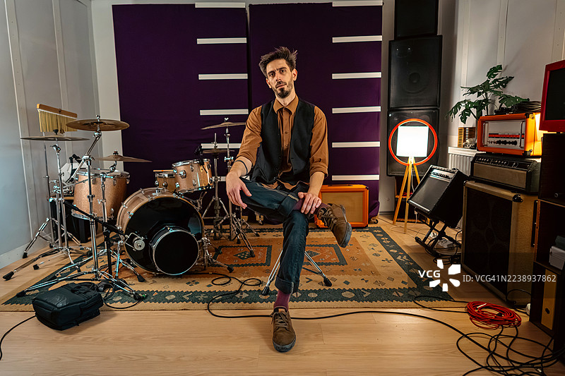 音乐制作人在充满活力的录音棚里，周围摆满了鼓和复古设备，正在进行录制。图片素材