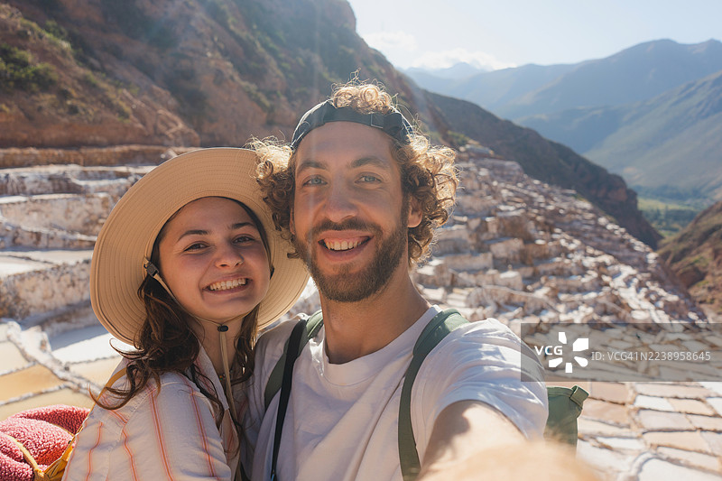 一对开心的情侣在秘鲁旅行期间，在马拉斯盐田自拍图片素材