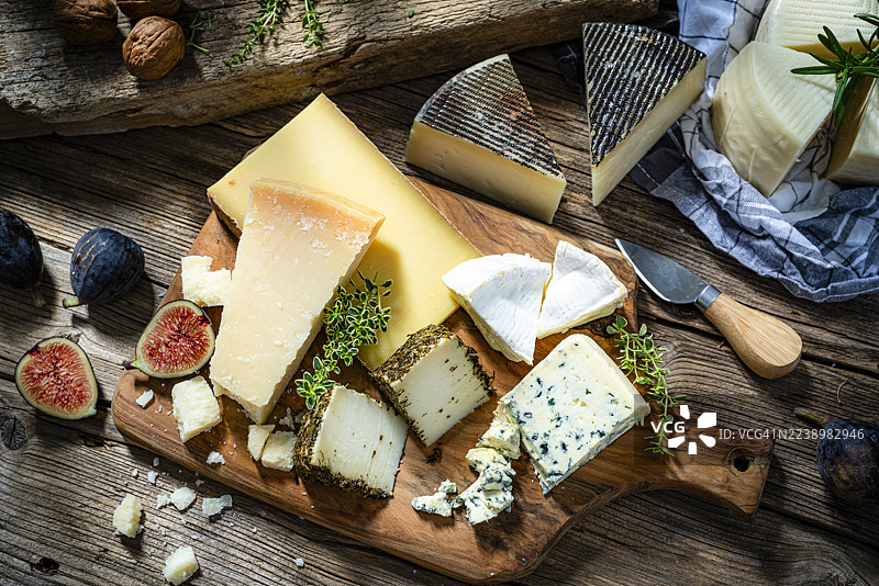 俯拍的美味奶酪拼盘放在木桌上。精选奶酪：帕玛森奶酪、蓝纹奶酪、曼彻戈奶酪。法式或地中海风味美食。派对或晚餐的美味开胃菜。图片素材