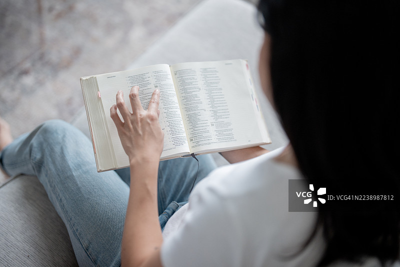 女人在家坐在沙发上阅读打开的书，休闲学习时刻图片素材