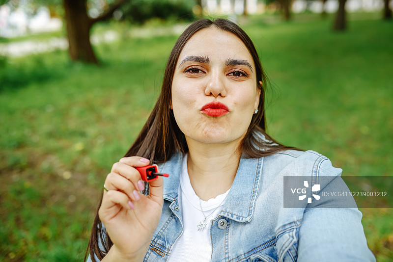 坐轮椅的金发女郎涂口红，展现女性魅力瞬间。图片素材