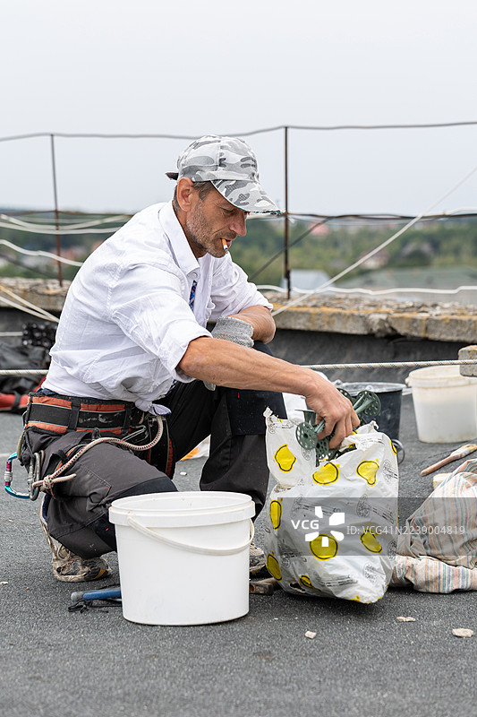建筑工人将用于固定聚苯乙烯板的塑料锚栓放入桶中。图片素材