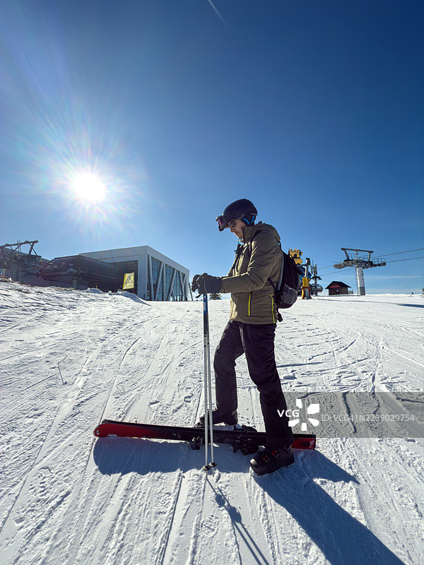 滑雪胜地，一名滑雪者站在斜坡上，背景是明媚的阳光和缆车。图片素材