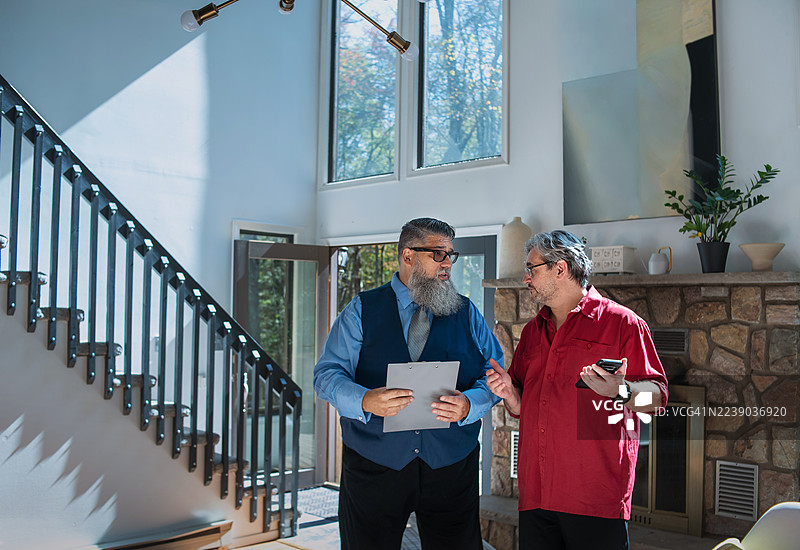 宾夕法尼亚州房产内，在高天花板下，人们围绕着石砌壁炉进行房屋参观讨论。图片素材