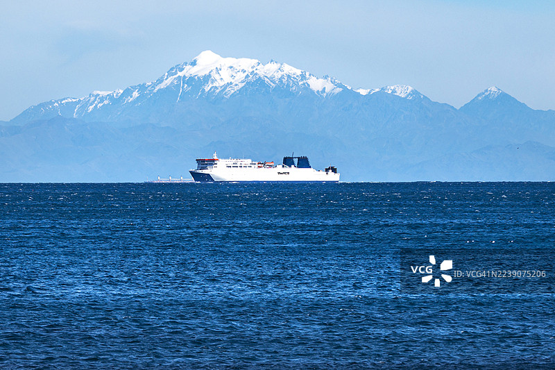 茫茫大海的地平线上，一艘大型渡轮和一座雪山图片素材