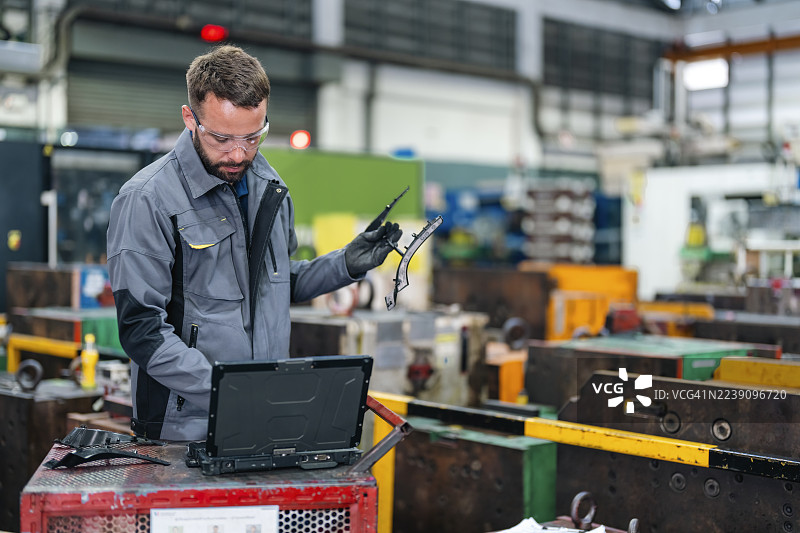汽车内饰制造厂，一名工人正在传送带旁检查产品质量。图片素材