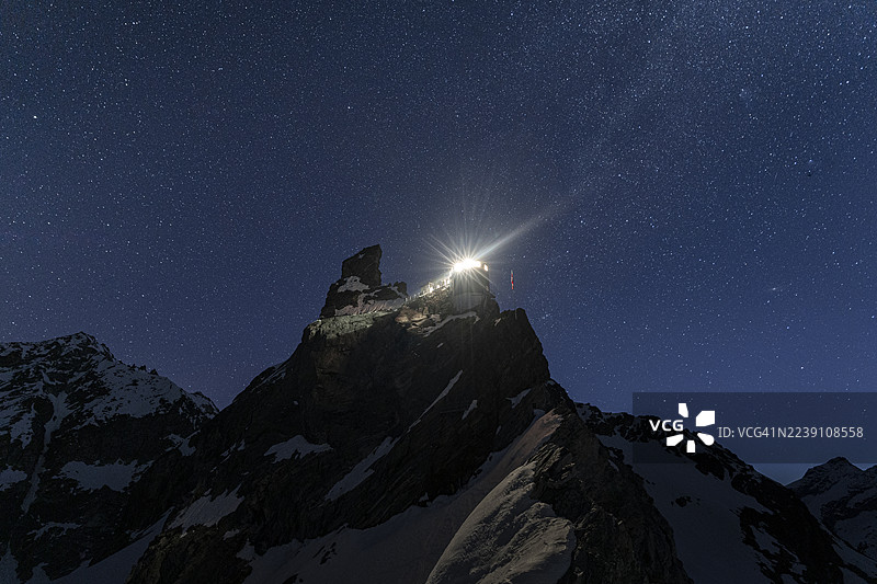 岩石山峰上的高山小屋上方的星空图片素材