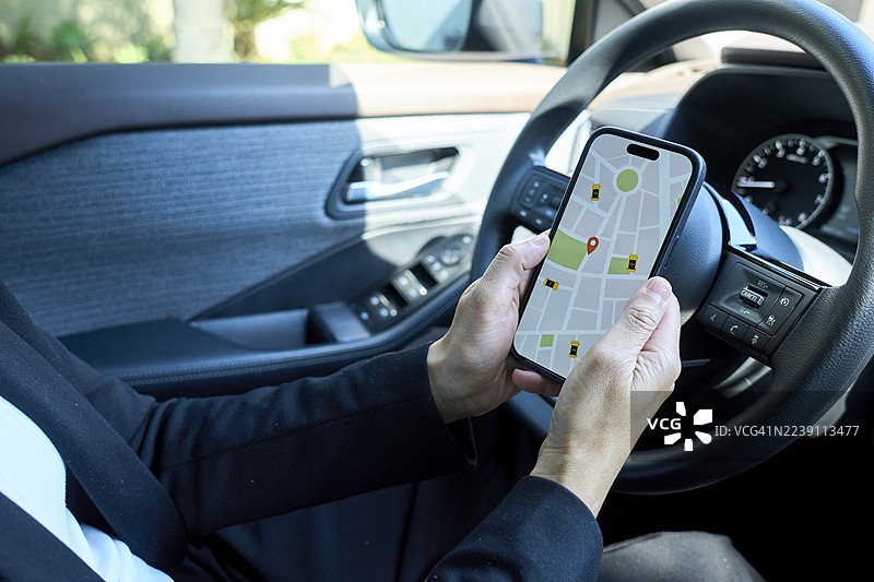 一个人在车里，手里拿着带有网约车应用的智能手机图片素材