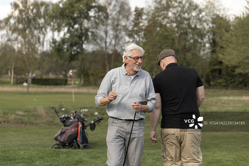 欧洲退休老人与红发球童打高尔夫球图片素材