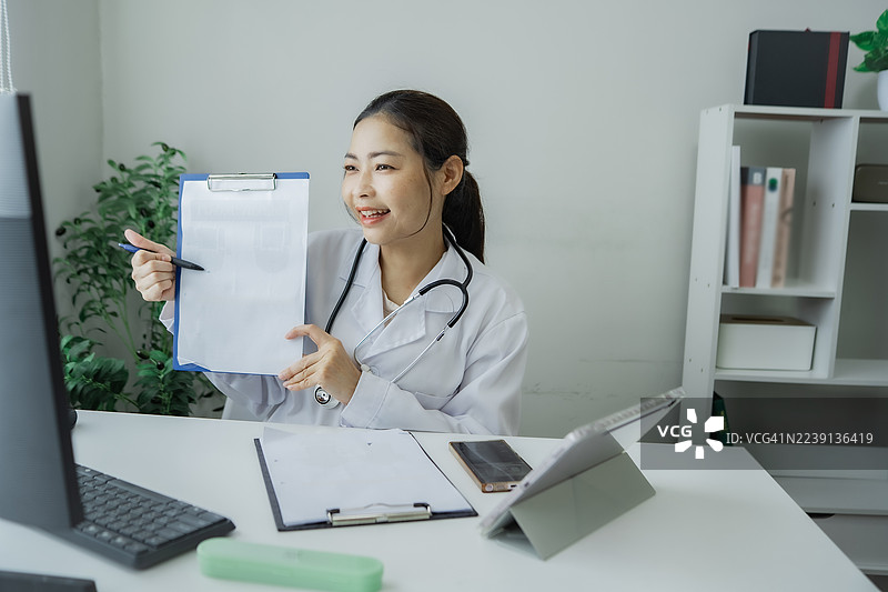 自信的护士手持文件夹坐在明亮的诊所，专注于以远程医疗为概念的患者护理和病历管理。图片素材