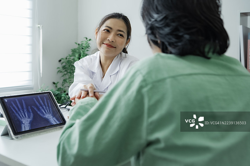 一位女性医护人员理解地倾听患者心声并握住她的手，展现了医学中的同理心。图片素材